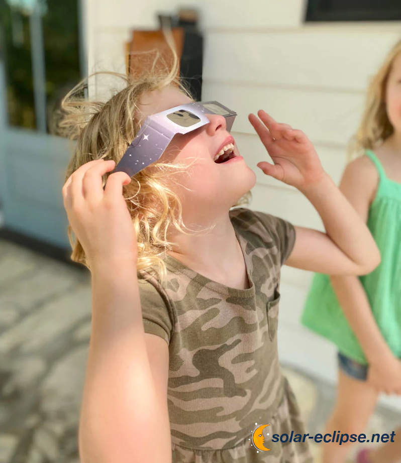 girl wearing solar eclipse glasses looking up